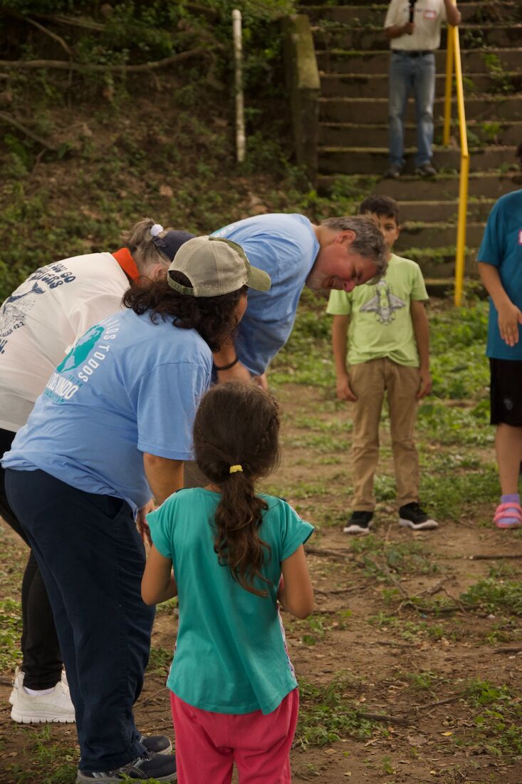 Team members working outdoors alongside local children on a hillside in El Salvador