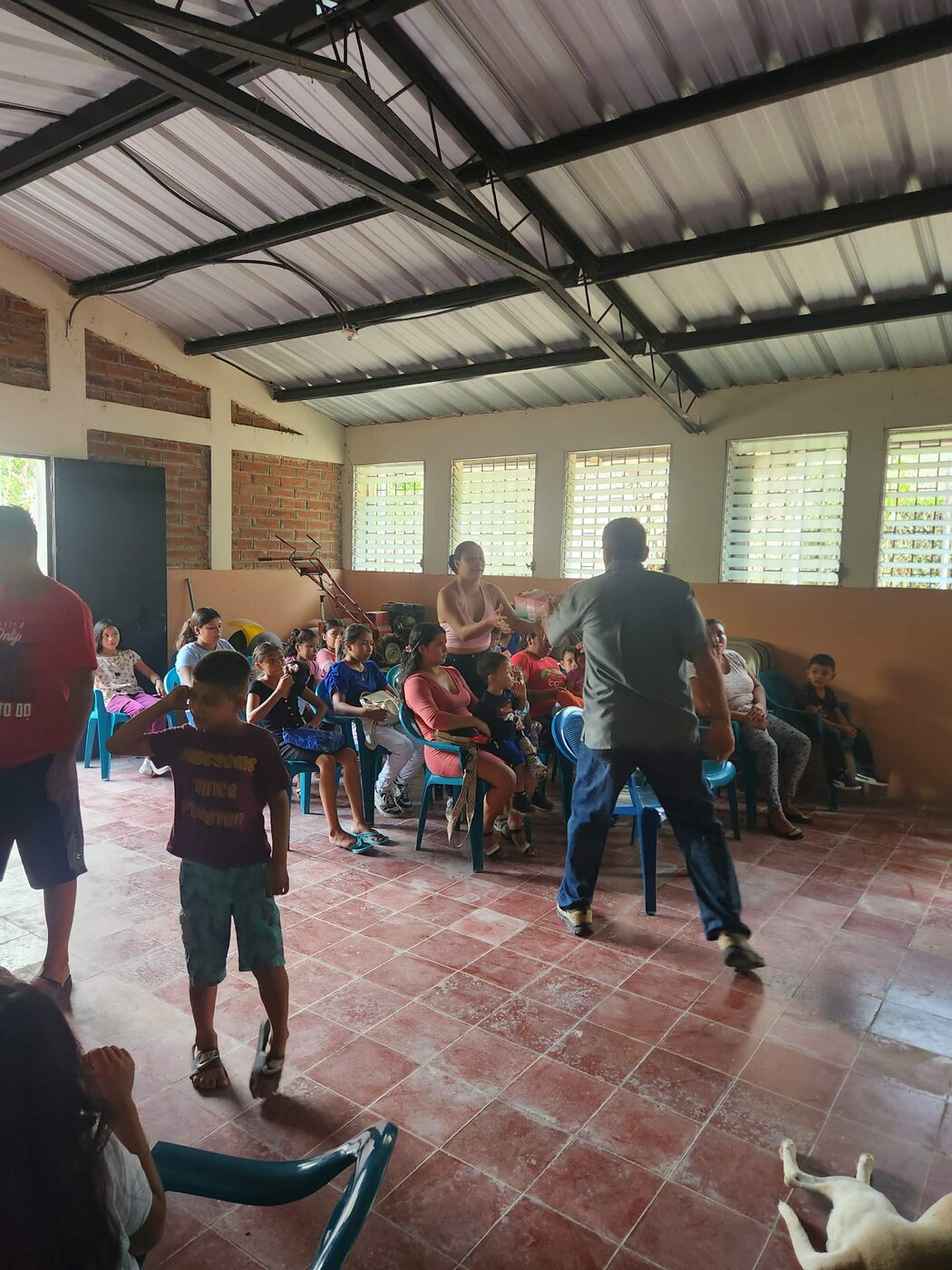 Children sit together in an open-air pavilion in El Salvador waiting to receive Operation Christmas Child shoebox gifts