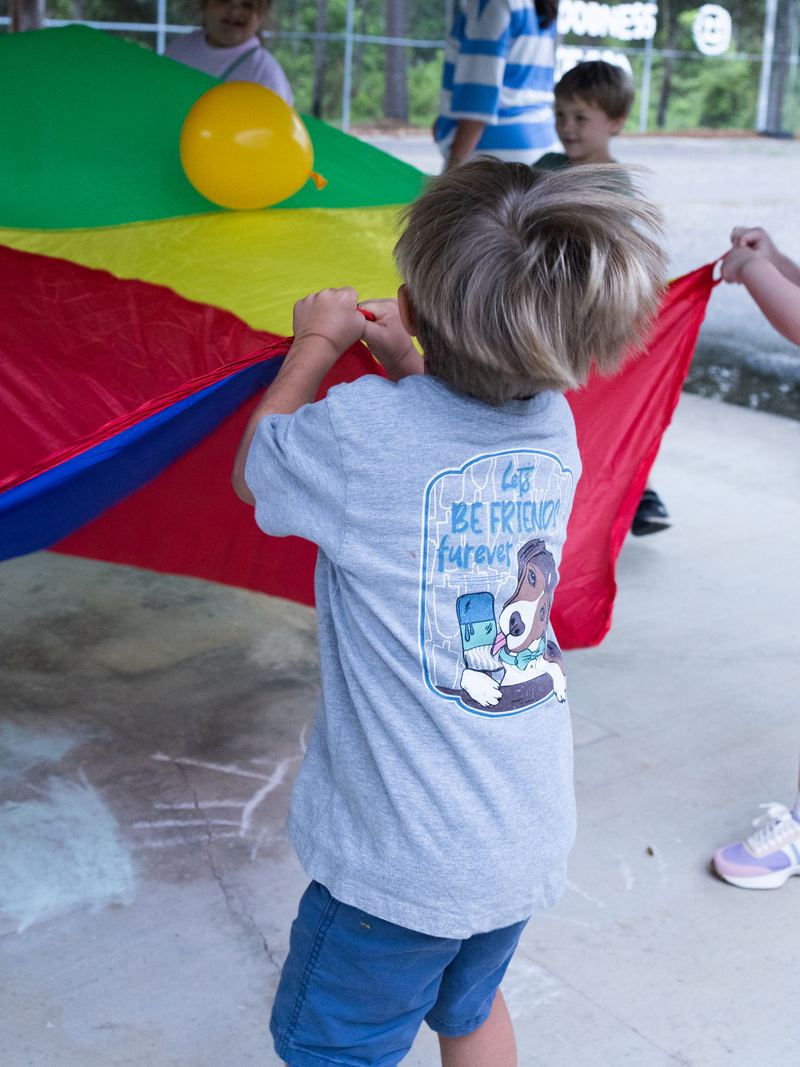 Children playing a parachute game at VBS 2026